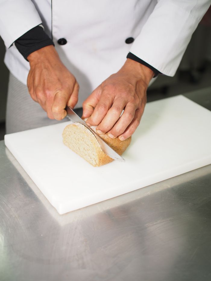 services-04 Chef slicing fresh bread on a cutting board with precision and care.
