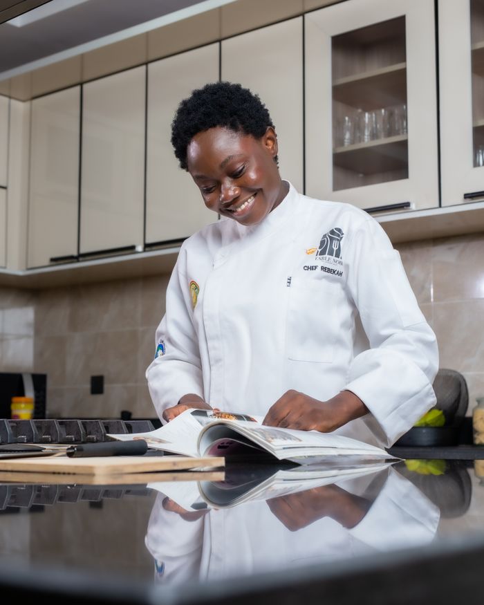 Friendly chef exploring new recipes in a sleek kitchen setting, perfecting culinary art.