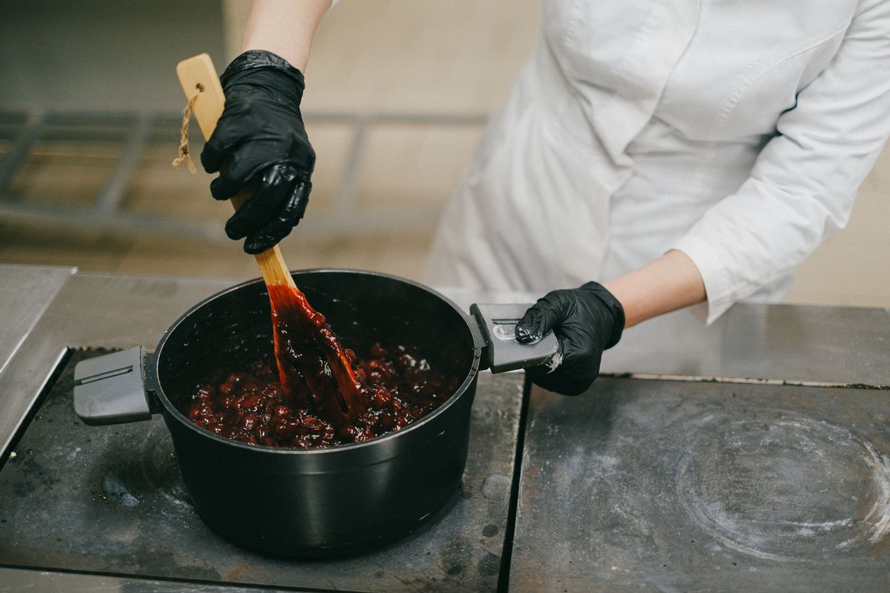 Mastering the First Impression: Your intriguing post title goes here Chef stirring sauce in a pot with black gloves, showcasing food preparation techniques.